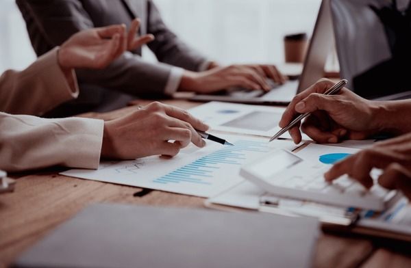 Affärsmöte där kollegor analyserar diagram och budget inför en konferens.